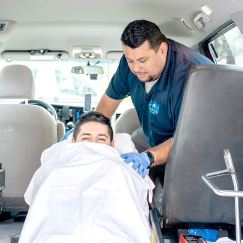 a staff assisting a patient on a stretcher inside a van