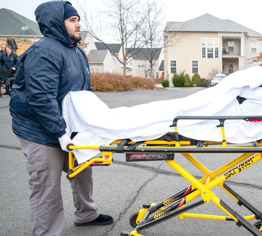 a man lifting a stretcher with a patient into a vehicle