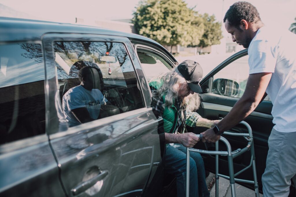 Client getting ambulatory transport services and help with getting out of a van with a walker.