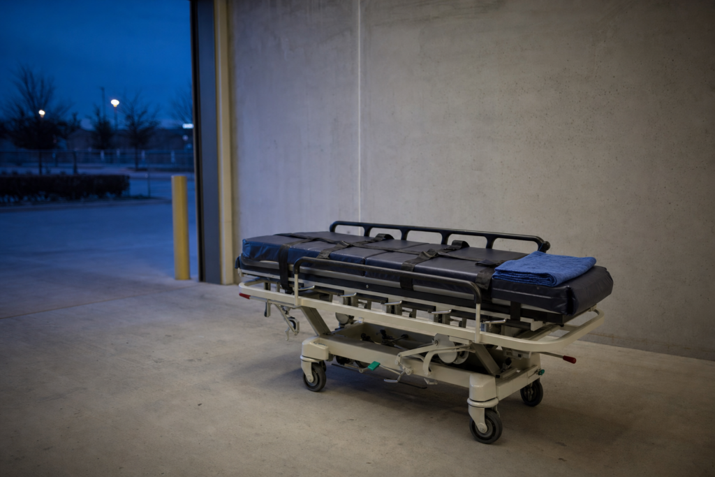 A reinforced heavy-duty stretcher with wide safety straps in a quiet loading bay