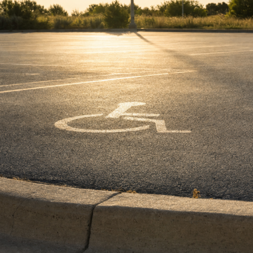 Empty sun-baked asphalt parking lot with heat haze and a faded accessible parking symbol on the ground